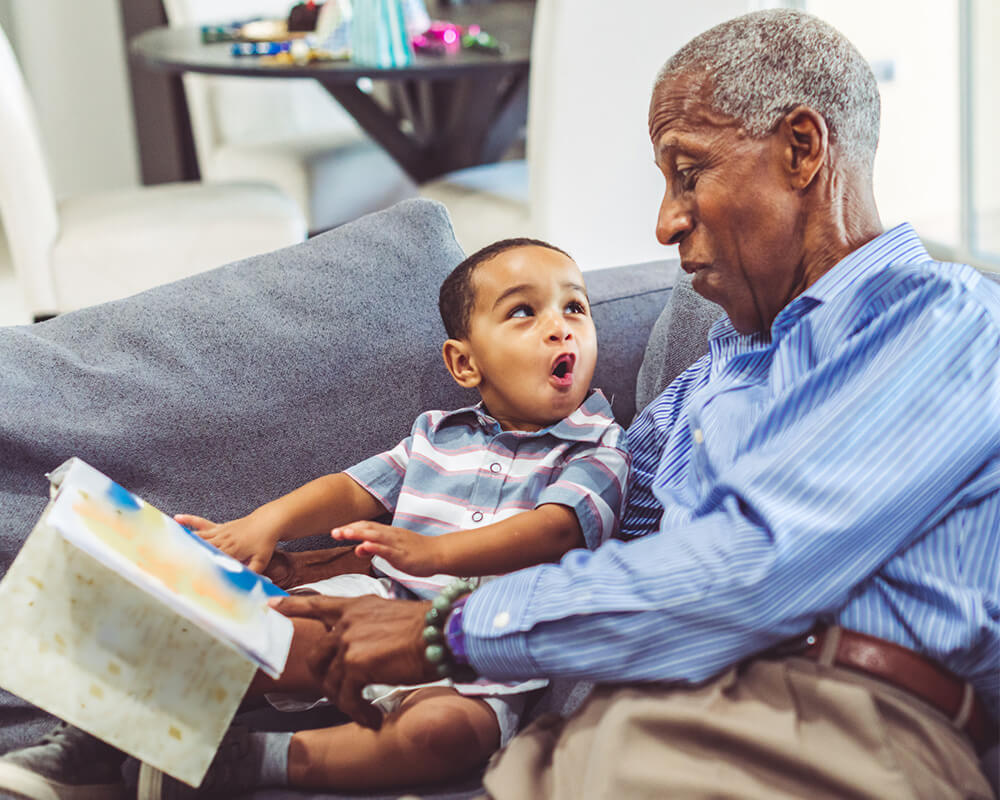 Senior grandfather and young grandson make a face during the reading of a book