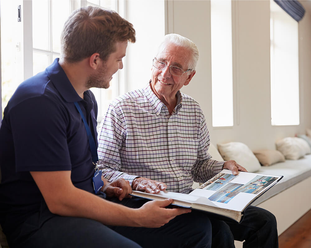 Senior man and adult son look through scrapbook