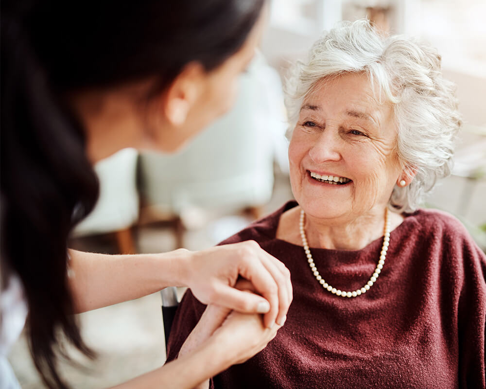 Senior woman holds hands with caregiver