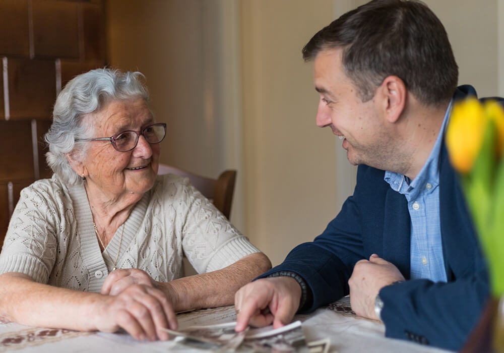 Professional man speaks to senior woman at a table
